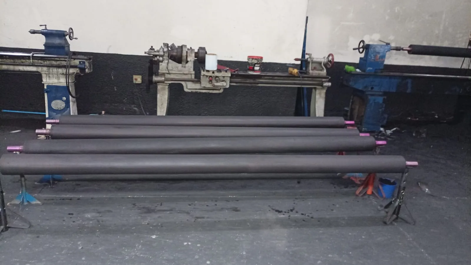 Rolos longos revestidos em borracha durante preparação para linha industrial